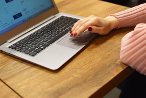 a woman using a laptop computer on a wooden table