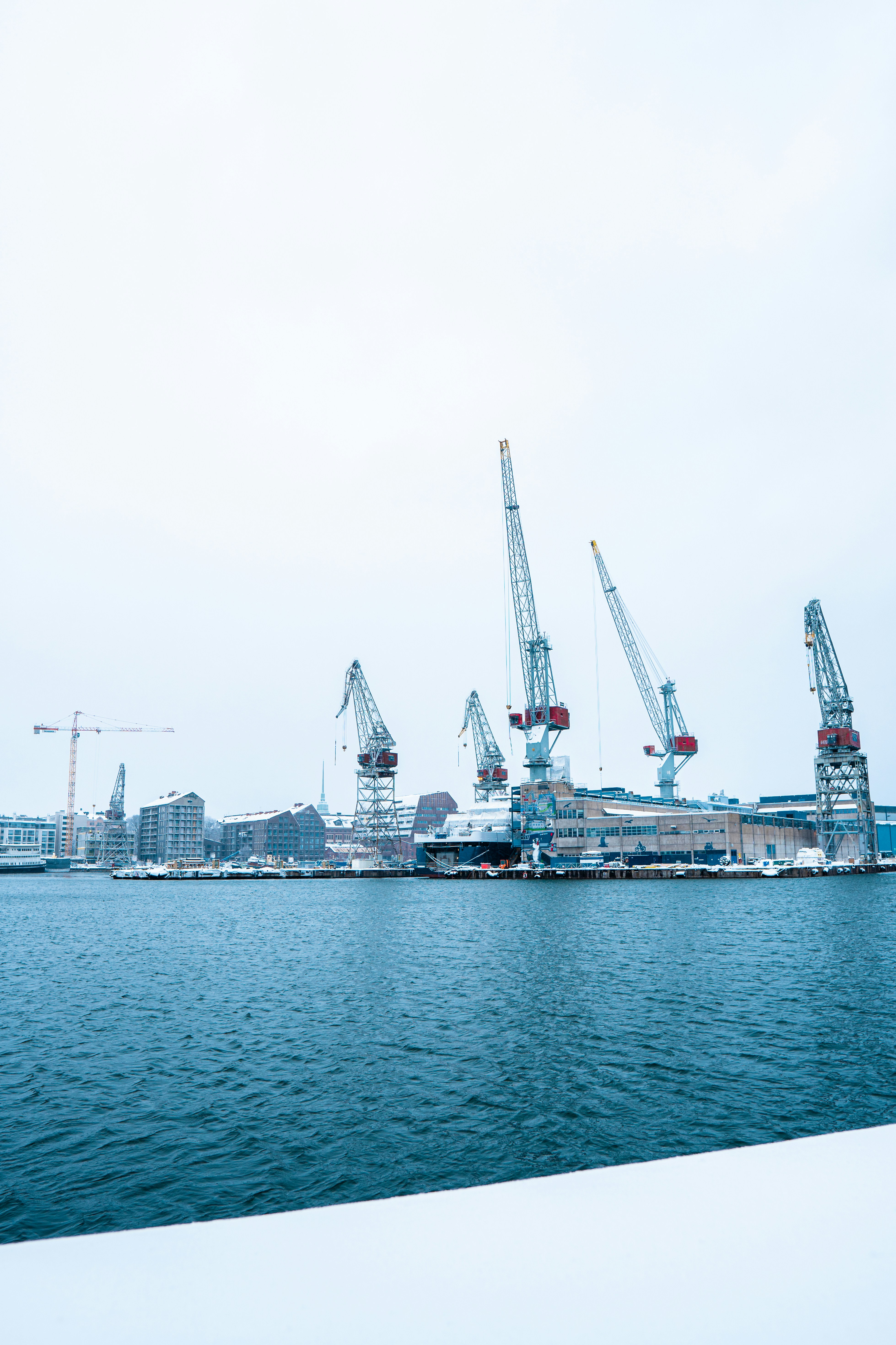 a large body of water with cranes in the background