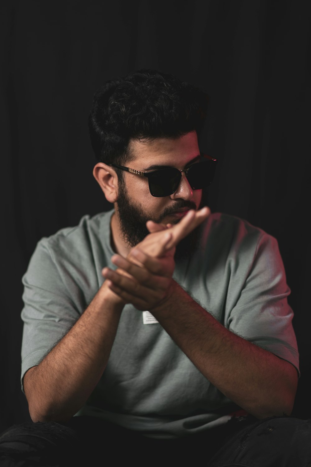 a man with a beard and sunglasses sitting in front of a black background
