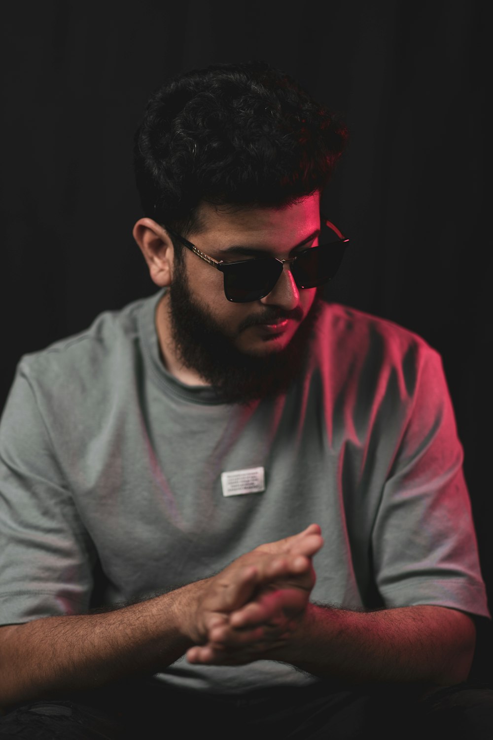 a man with a beard and sunglasses sitting in front of a black background