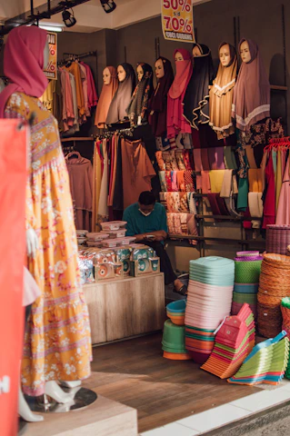 a woman sitting in front of a store filled with colorful items
