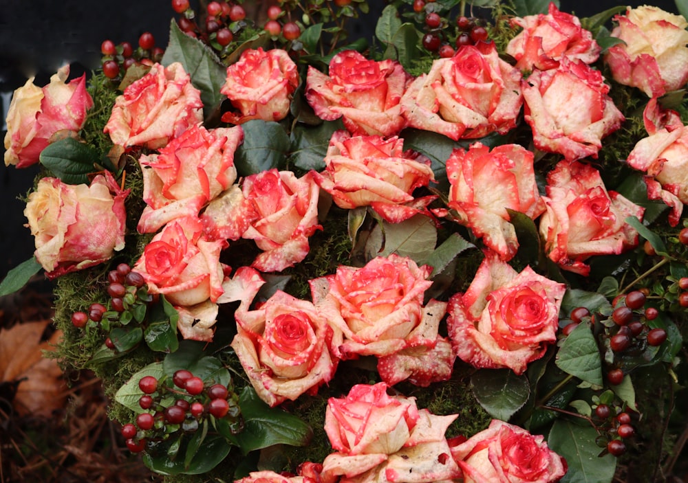 a bunch of red and yellow roses with green leaves