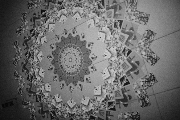 A kaleidoscope pattern composed of various images, predominantly featuring architectural elements and geometric shapes. The design forms a circular, symmetrical mandala-like structure with intricate details.