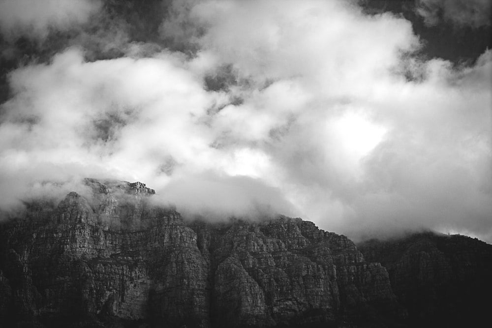 a black and white photo of clouds over a mountain