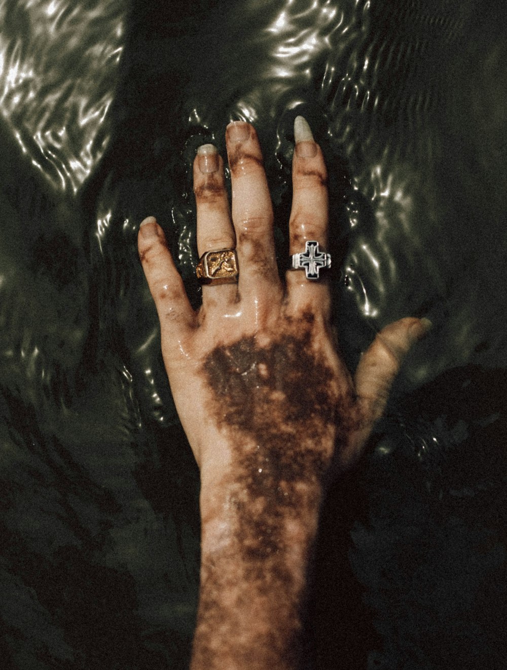 a person's hand with a ring on it in the water