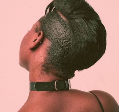 a woman with a shaved head wearing a leather choker