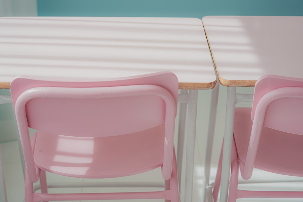 two pink chairs sitting next to each other at a table
