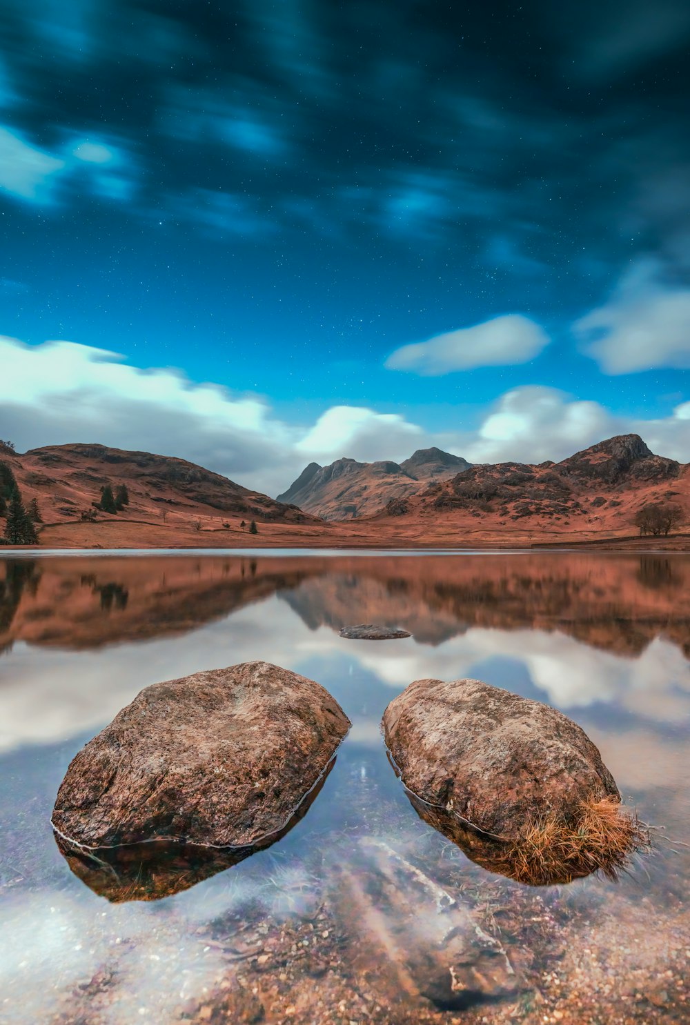 two rocks sitting on top of a lake under a cloudy sky