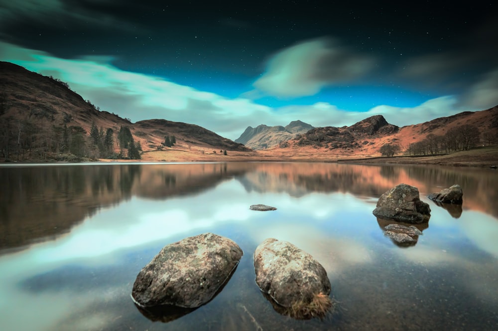 a lake surrounded by mountains under a cloudy sky