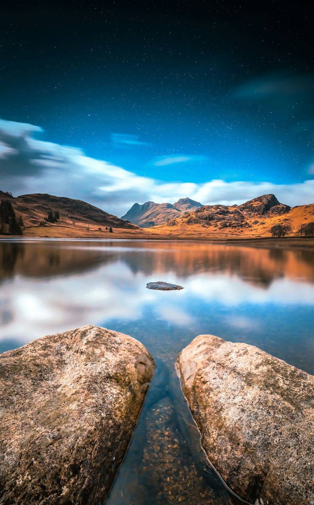 Due grandi rocce sedute sulla cima di un lago sotto un cielo notturno