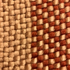 A close-up view of a woven fabric featuring interlocking strands of beige and reddish-brown threads. The texture of the fabric is coarse, highlighting the thick yarns used in the weaving process.