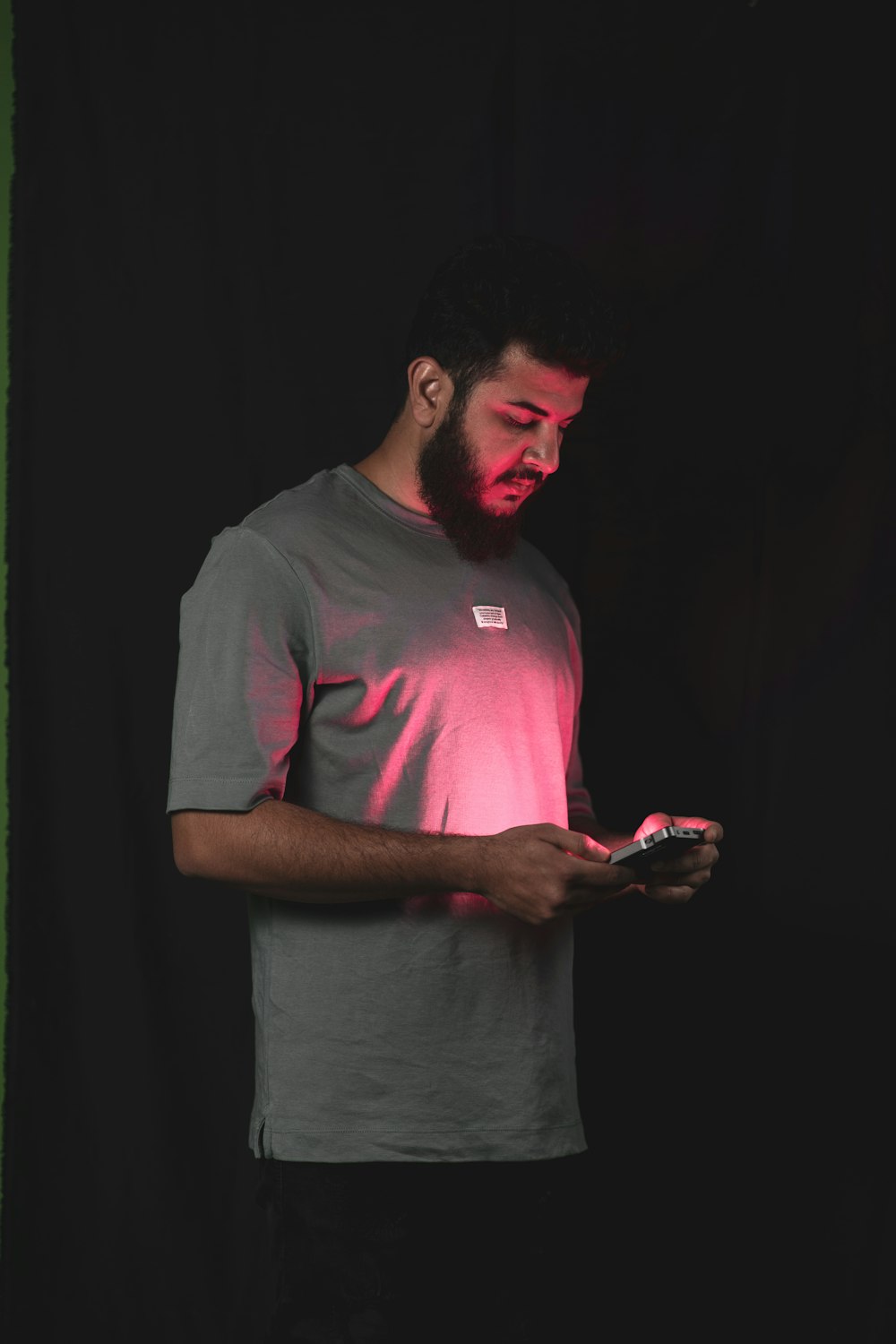 a man standing in a dark room looking at his cell phone