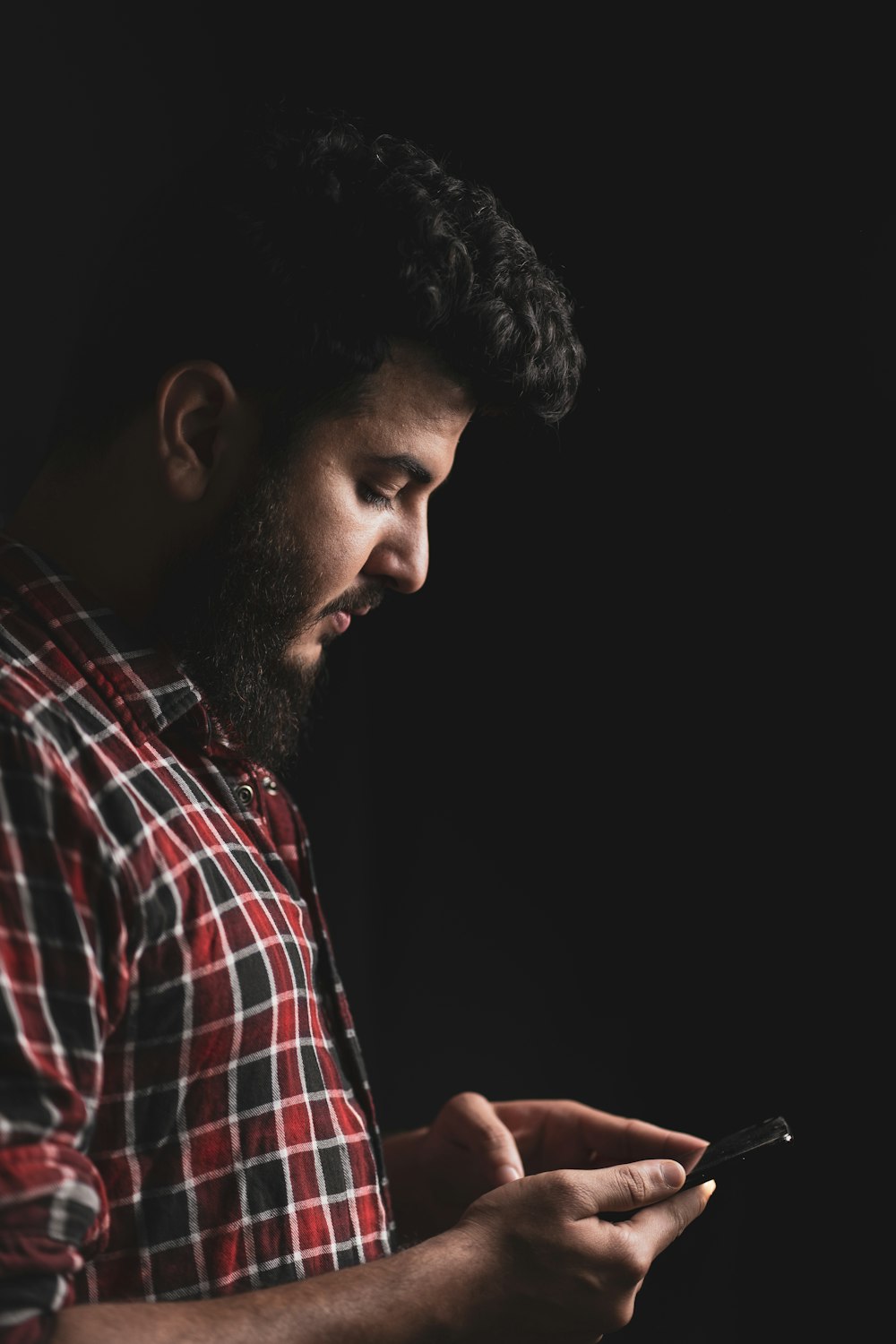 a man with a beard is looking at his cell phone