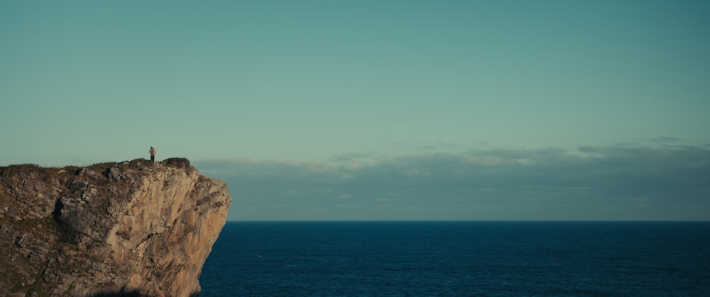 a person standing on the edge of a cliff overlooking the ocean