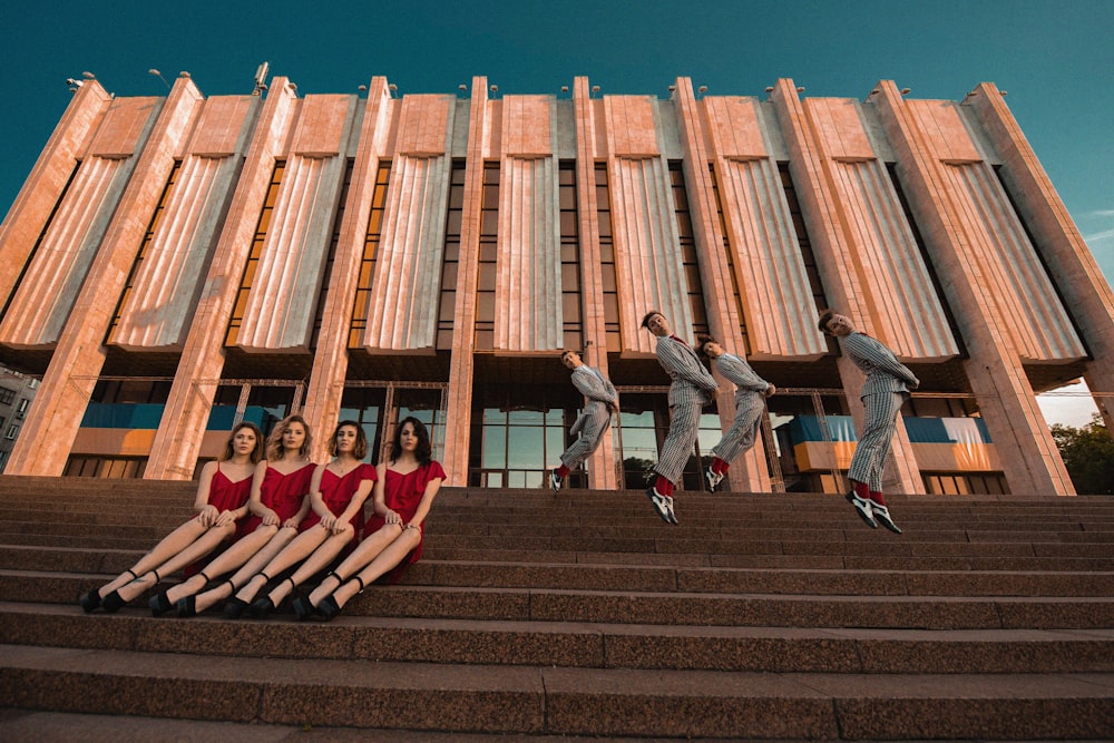 a group of women in red dresses sitting on the steps of a building