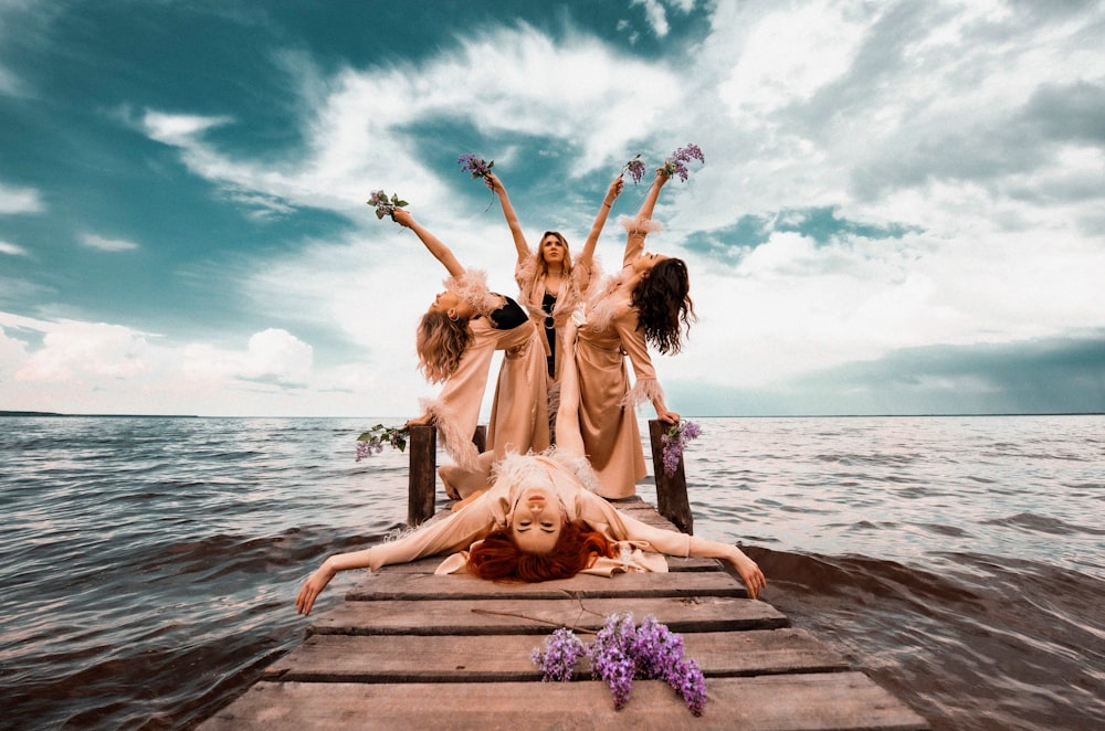 a group of women standing on top of a wooden pier