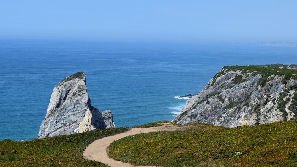 a path leading to two large rocks in the ocean