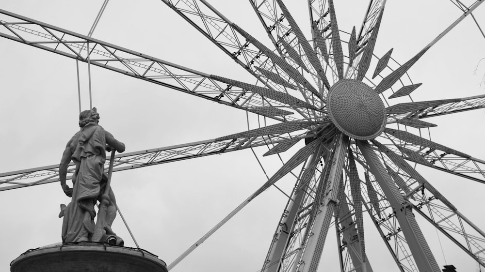 a statue of a man standing next to a ferris wheel