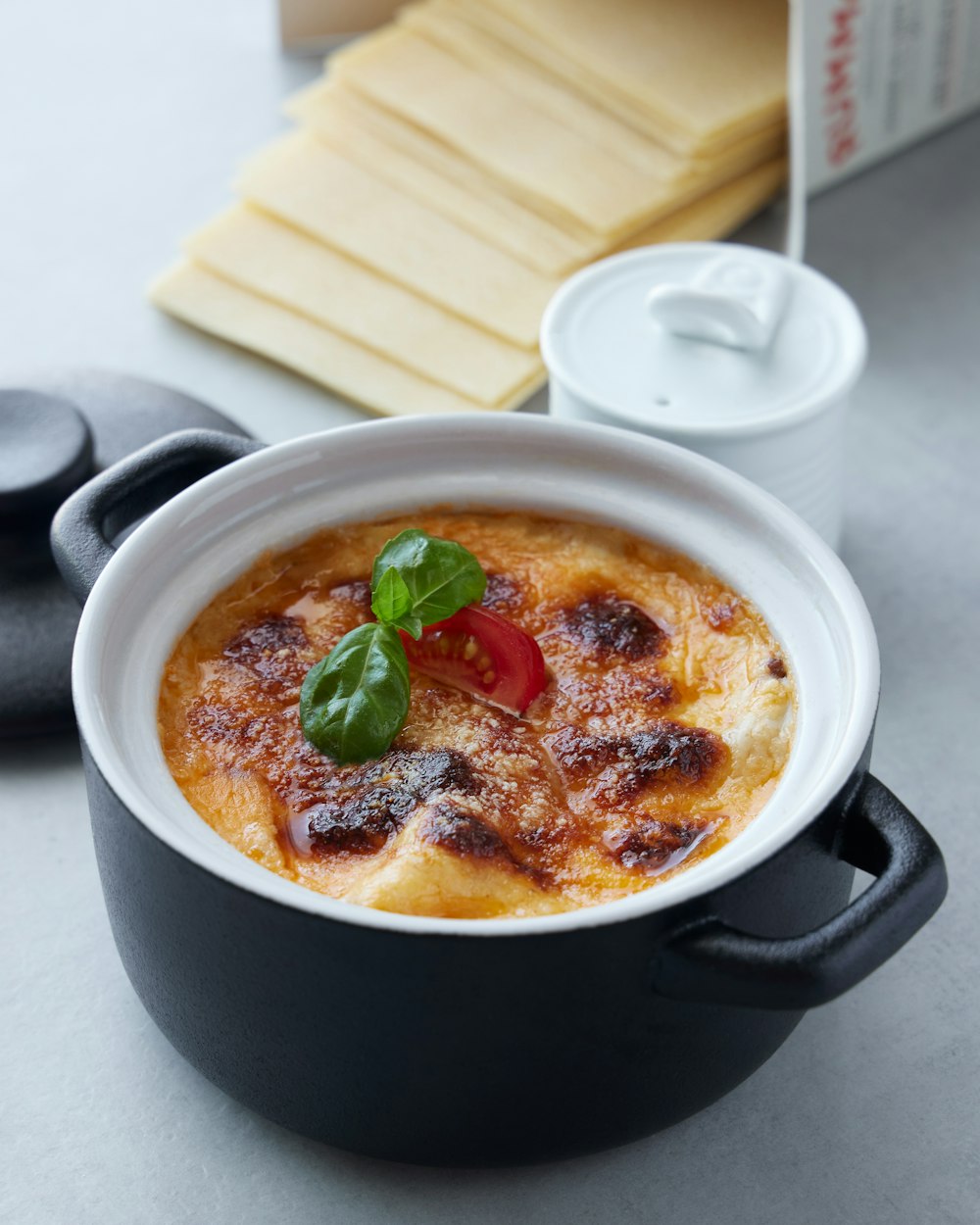 a bowl of food on a table next to a box of cheese