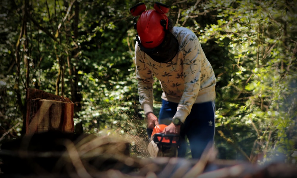 a man with a chainsaw cutting wood in the woods