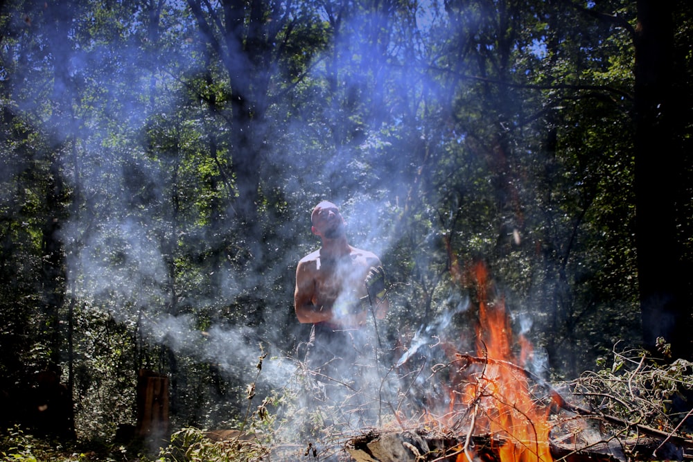 a man standing in front of a fire in the woods