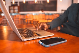 Person using a laptop and smartphone to communicate in a modern office space