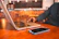 Young man using smartphone and laptop in cozy coworking space.