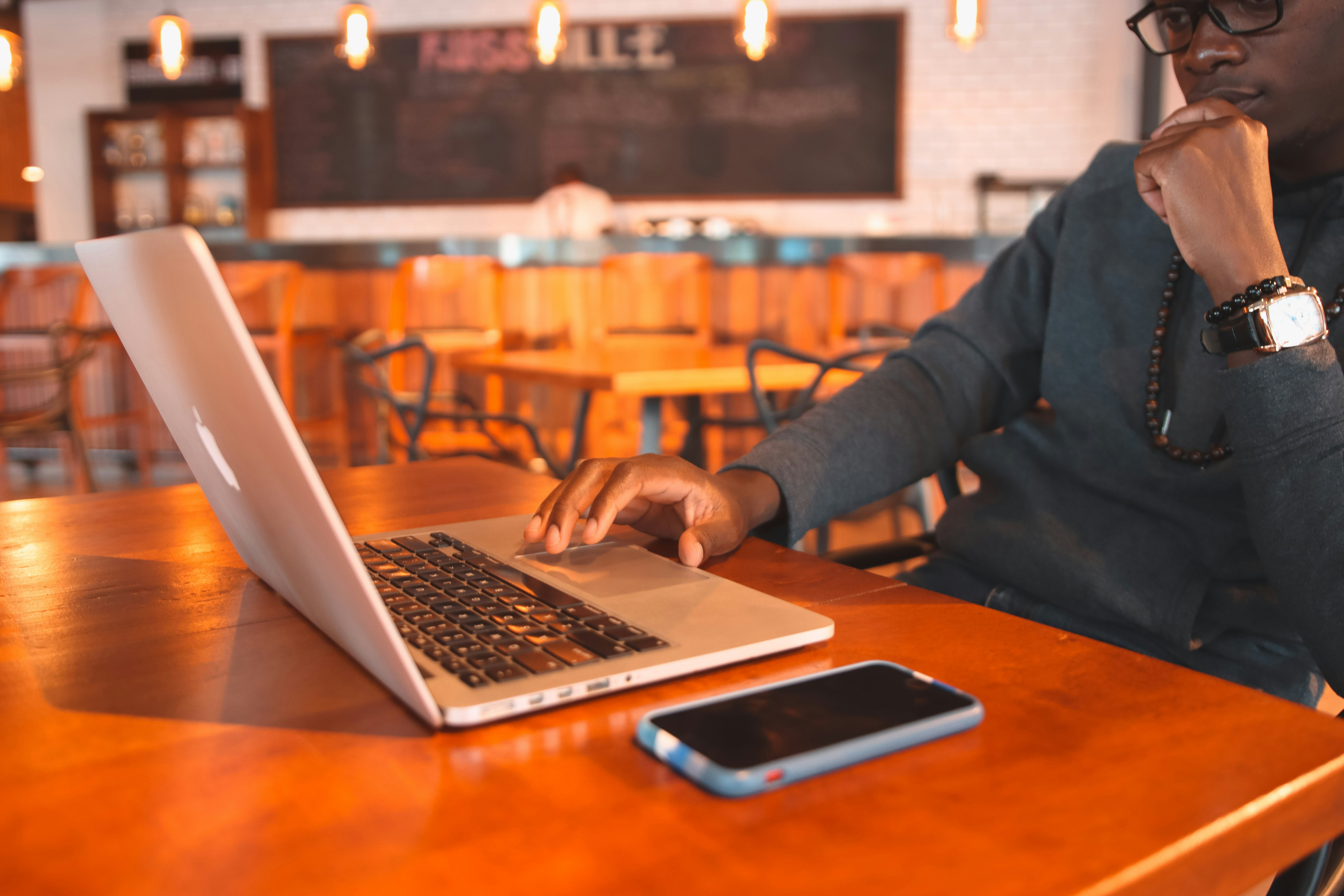 Um Homem Sentado Em Uma Mesa Usando Um Computador Portatil 3jy03i Dh74