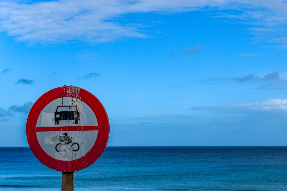 a red and white sign sitting on the side of a beach