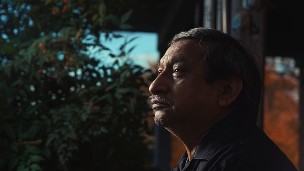 a man standing in front of a tree looking off into the distance