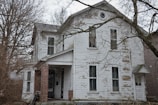 A rundown house with peeling paint and overgrown yard before renovation.