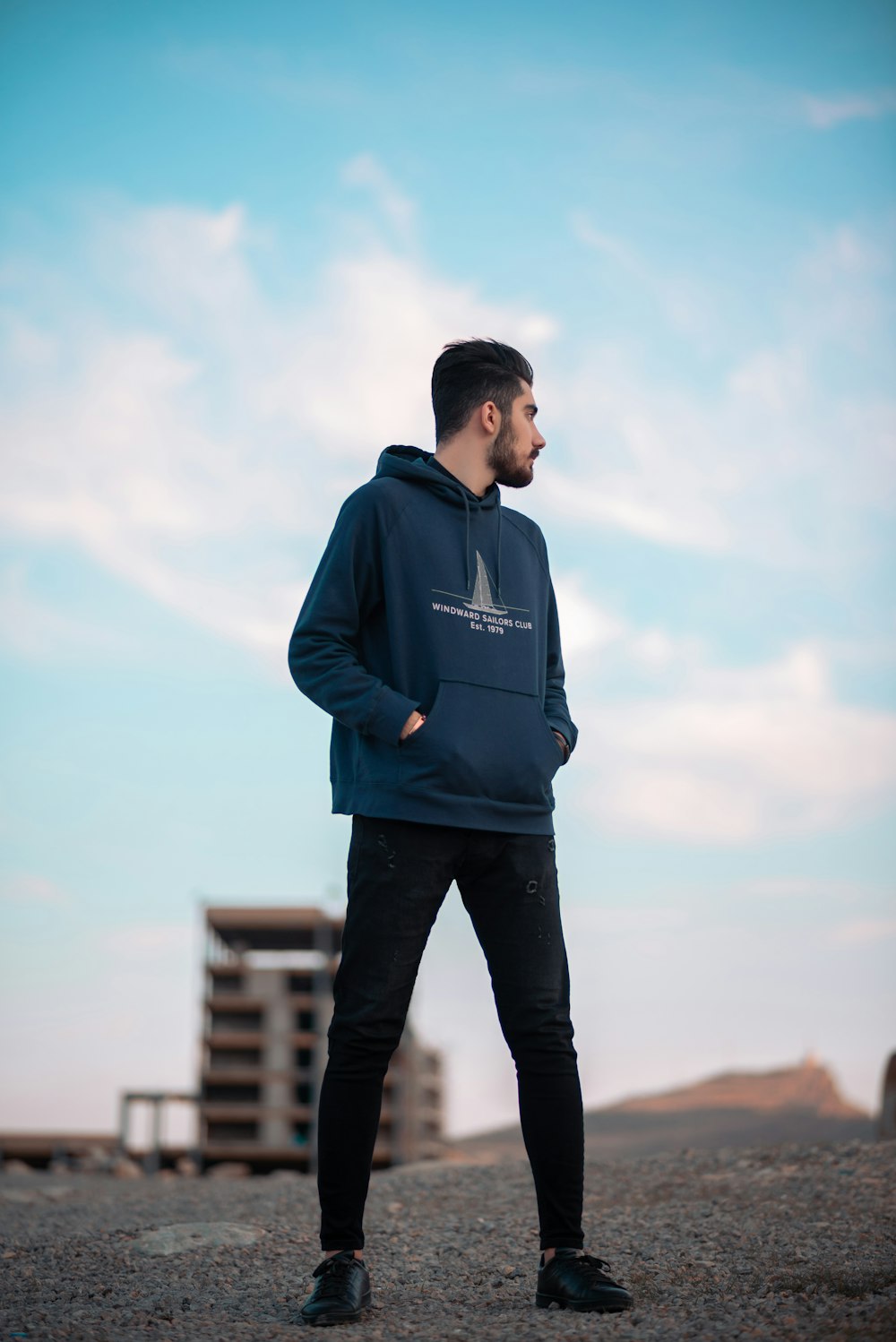 a man in a blue hoodie standing on a beach