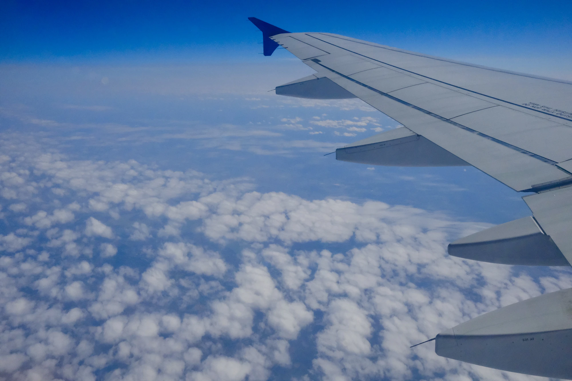 The wing of an airplane flying above the clouds