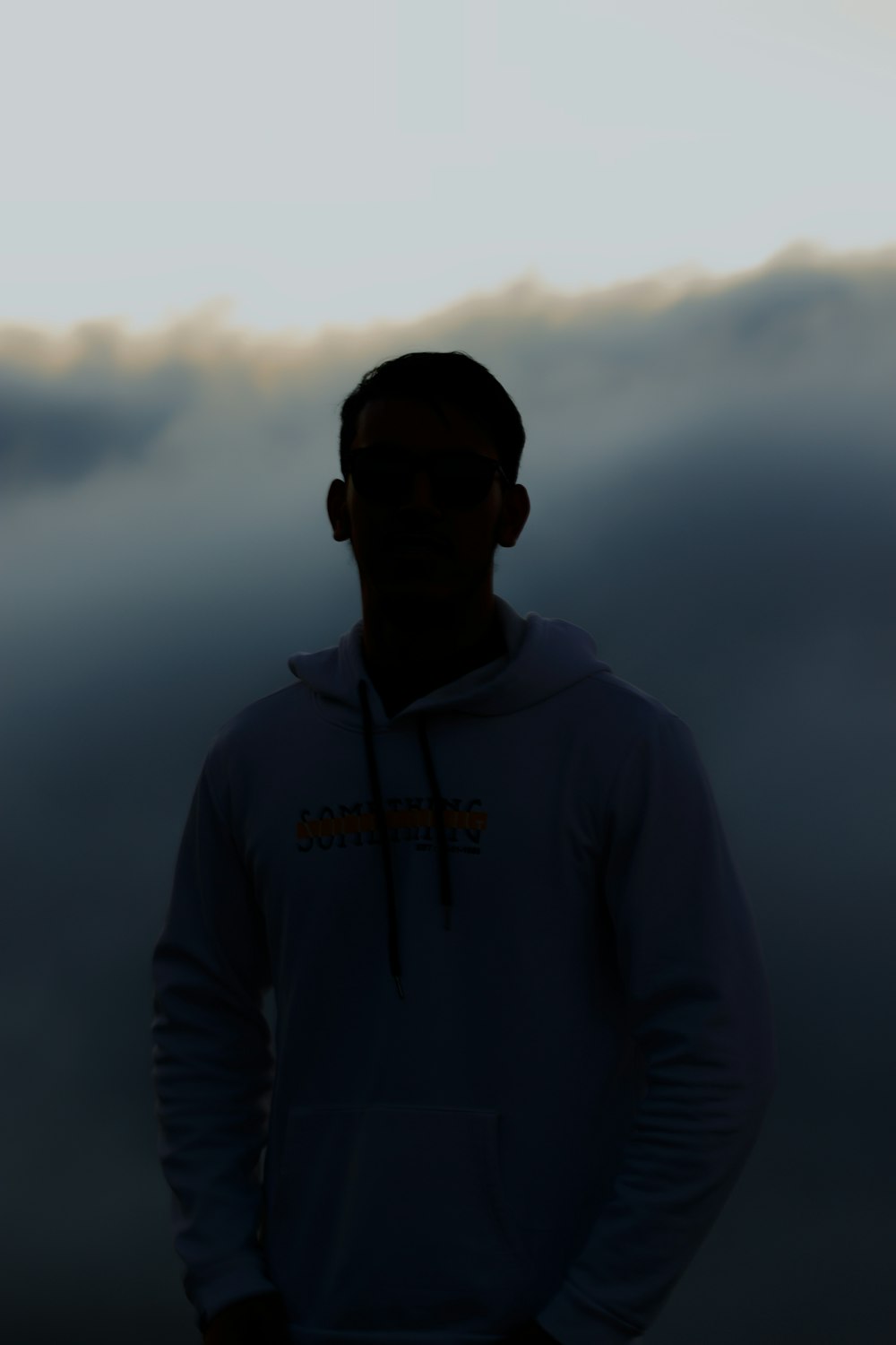 a man standing in front of a cloudy sky