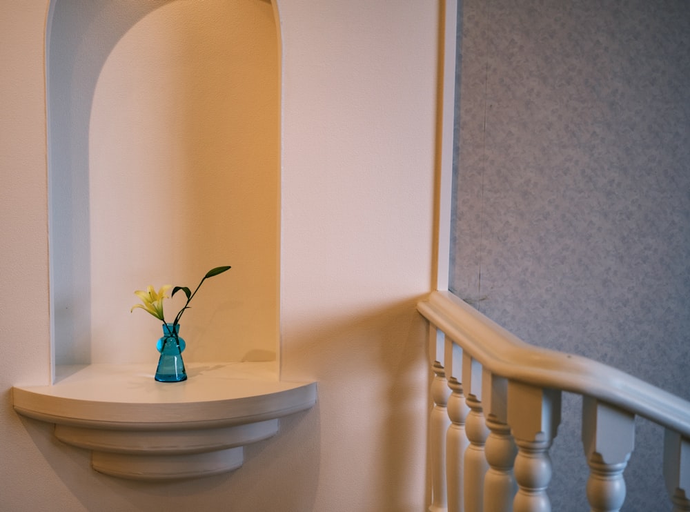 a vase with a flower in it sitting on a shelf