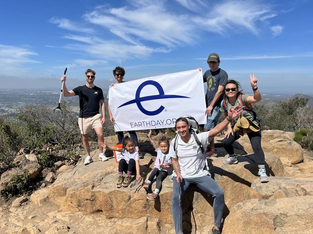 a group of people holding a sign on top of a mountain