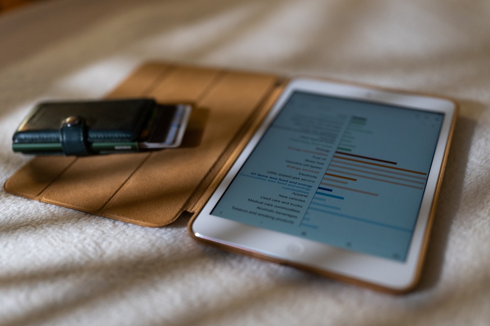 a tablet computer sitting on top of a bed next to a cell phone