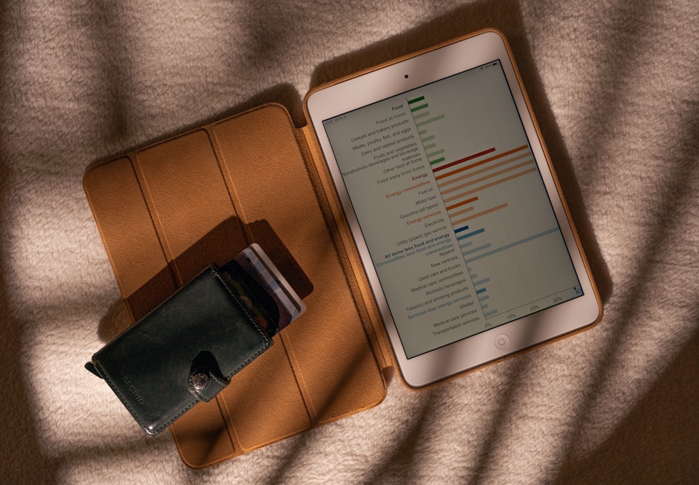 a tablet computer sitting on top of a table next to a wallet