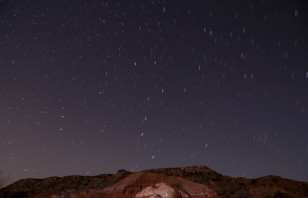 the night sky with stars above a mountain