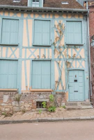 Exterior view of a renovated Saint Malo townhouse showcasing fresh paint and restored shutters.