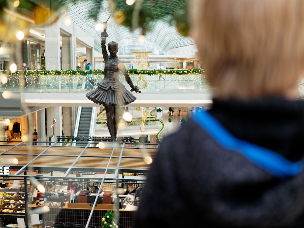 Une femme regardant une statue dans une vitrine de magasin