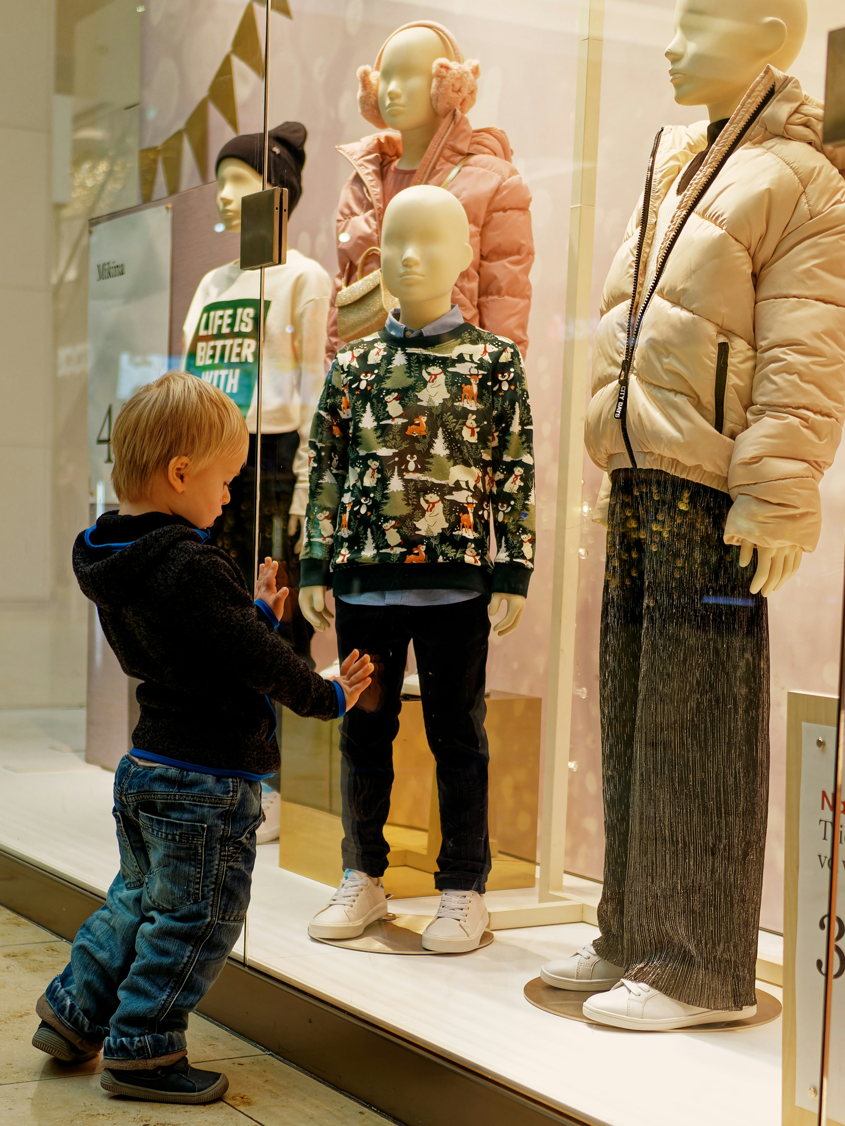 a little boy standing in front of a display of mannequins