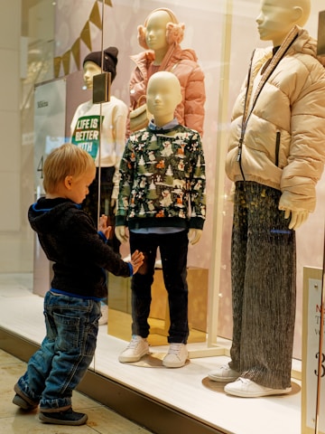 a little boy standing in front of a display of mannequins