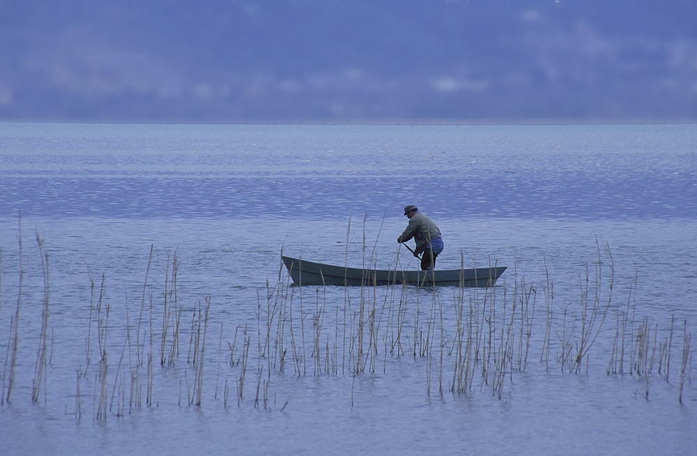 a man standing on a boat in the middle of a lake