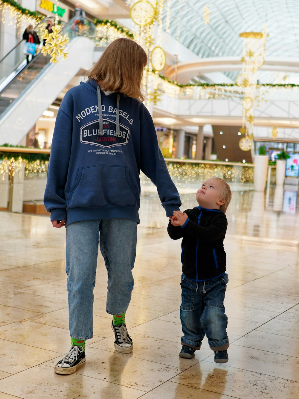 a woman holding the hand of a small child