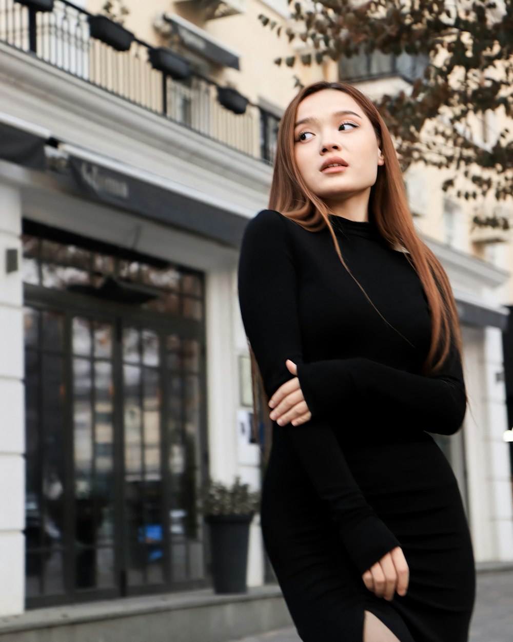 a woman in a black dress standing on a sidewalk