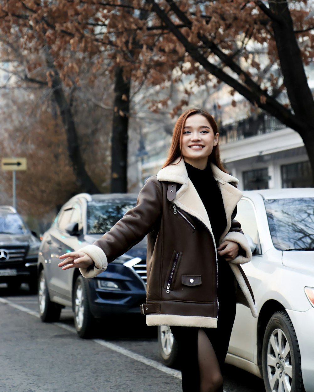 a woman walking down a street next to parked cars