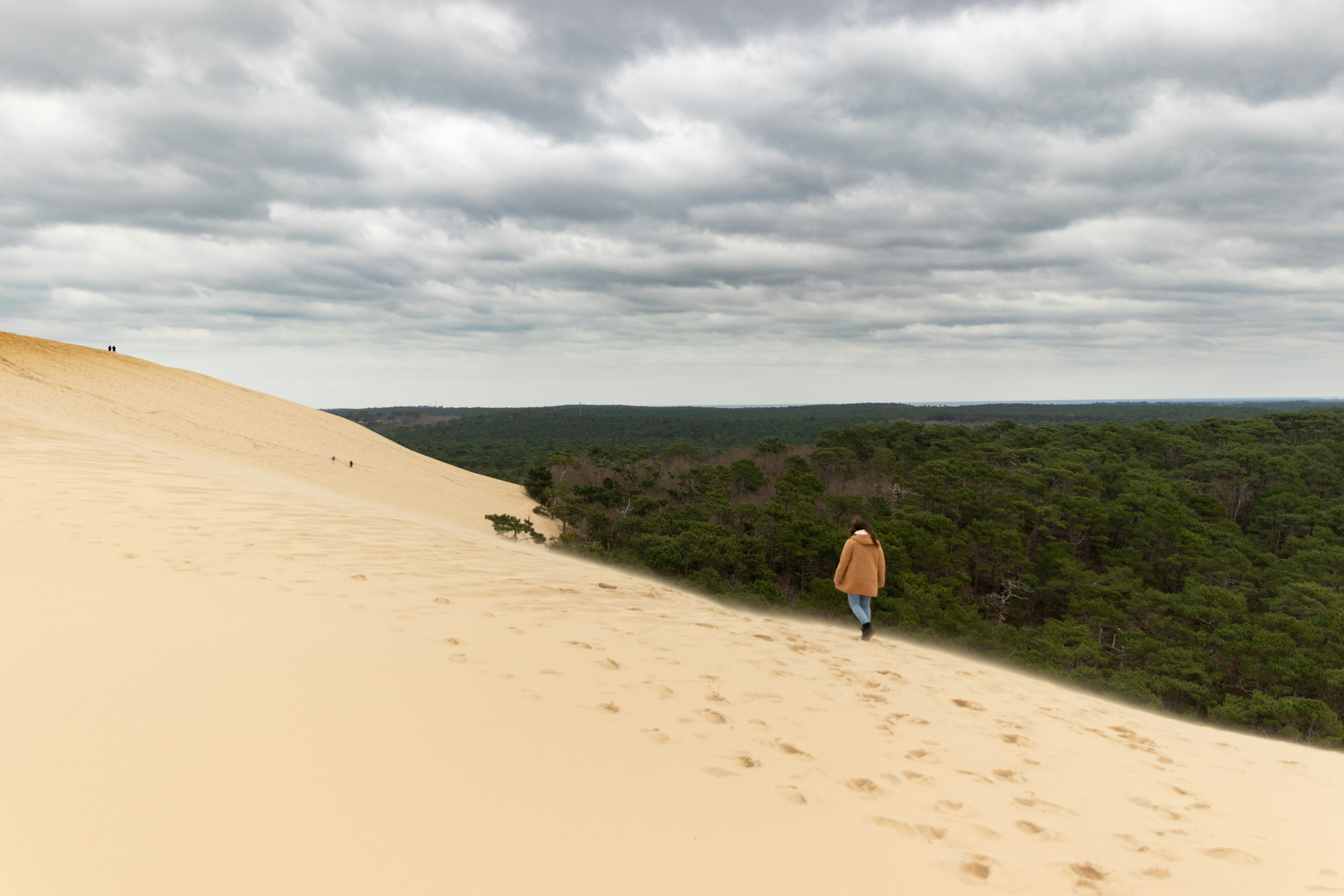 Una persona caminando por el lado de una duna de arena