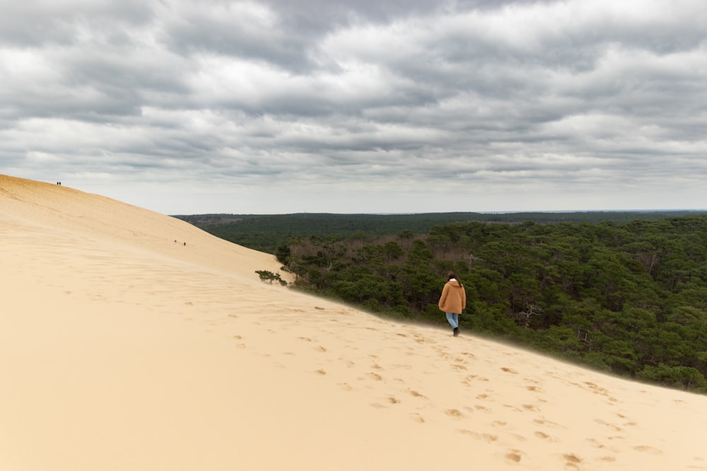 a person walking up the side of a sand dune