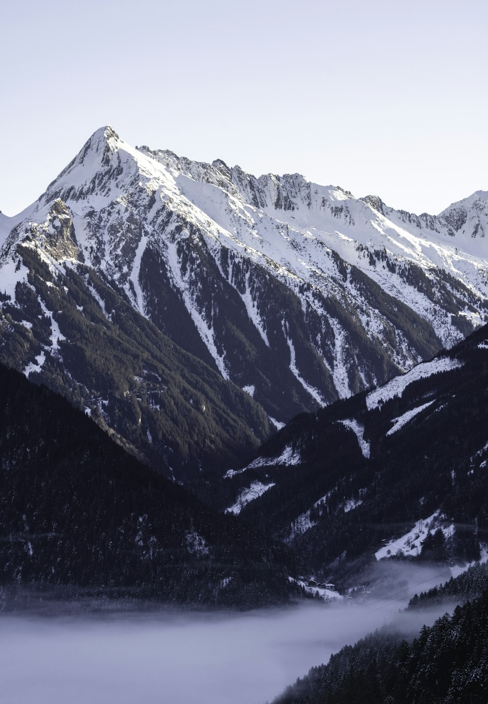 a mountain range covered in snow and fog